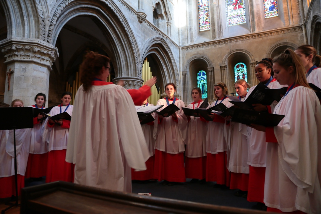 Seaford Chapel choir in their white and red robes singing in a traditional looking stone church building.