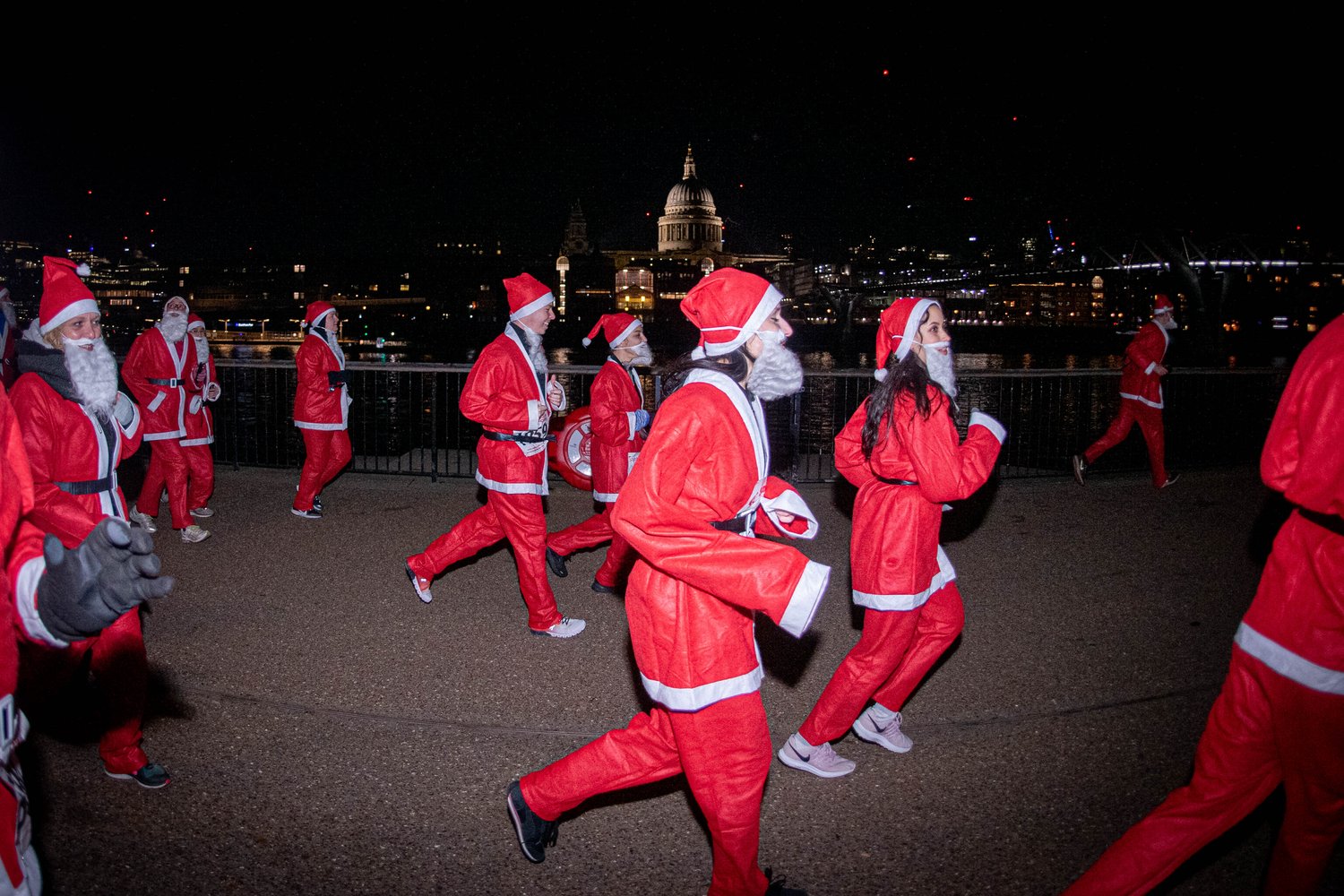 A group of adults dressed as Santa running passed St Paul's Catherdral.